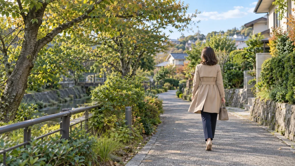 緑のある川沿いの道を歩く女性の後ろ姿