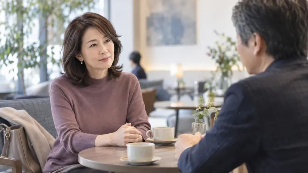 カフェで男性と向かい合い、静かに話を聞く女性
